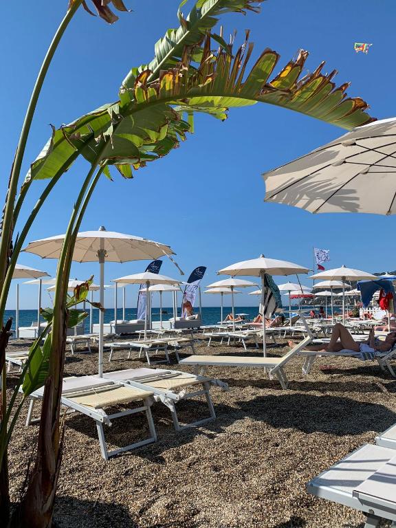 a group of tables and umbrellas on a beach at Appartamento SanBart Mare in San Bartolomeo al Mare