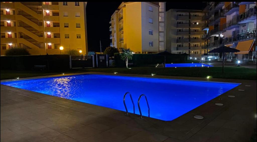 - une piscine bleue la nuit avec des bâtiments dans l'établissement Appartement 2 chambres avec 3 piscines et parking gratuit, à Roses