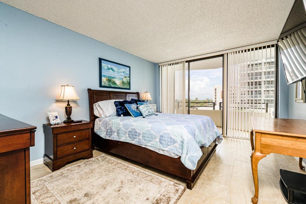 um quarto com uma cama, uma secretária e uma janela em Glorious Ocean Sunset Views 2 Bed 2 Bath Condo em Daytona Beach