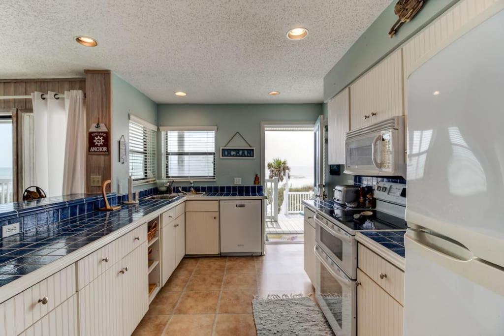 a large kitchen with white cabinets and blue counter tops at Tipsy Turtle Direct Oceanfront in Palm Coast