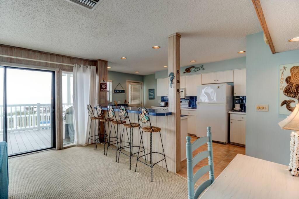 a kitchen with chairs and a counter with a refrigerator at Tipsy Turtle Direct Oceanfront in Palm Coast