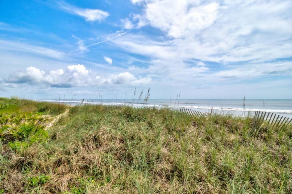 a sandy beach with a fence and the ocean at Tipsy Turtle Direct Oceanfront in Palm Coast