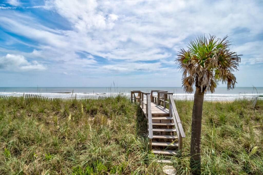 a staircase leading to a beach with a palm tree at Tipsy Turtle Direct Oceanfront in Palm Coast