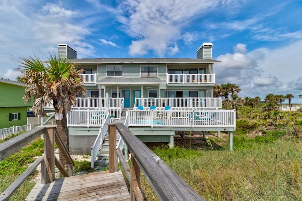 a house on the beach with a wooden boardwalk at Tipsy Turtle Direct Oceanfront in Palm Coast