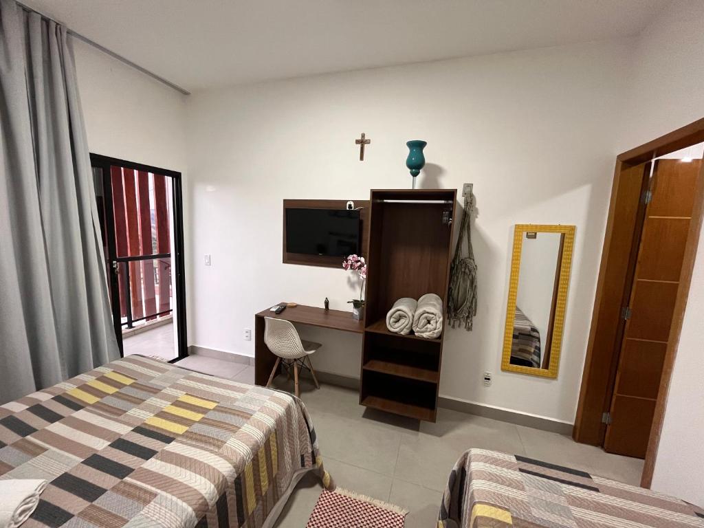 a bedroom with a bed and a desk and a tv at Estadia na Canção Nova in Cachoeira Paulista