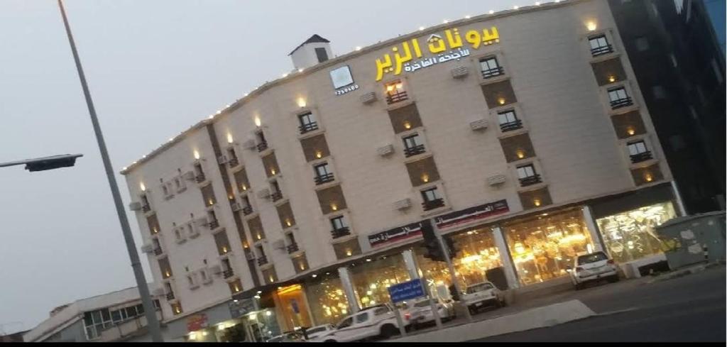 een groot gebouw met auto's geparkeerd voor het bij بيوتات الزير in Al Baha
