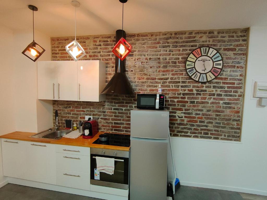 a kitchen with a brick wall and a clock on a wall at Les Lofts De Provins: Apt 5 in Provins