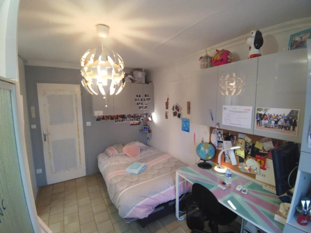 1 dormitorio con cama, escritorio y lámpara de araña en 5 min pole européen du cheval - 15min circuit 24 h, en Fatines