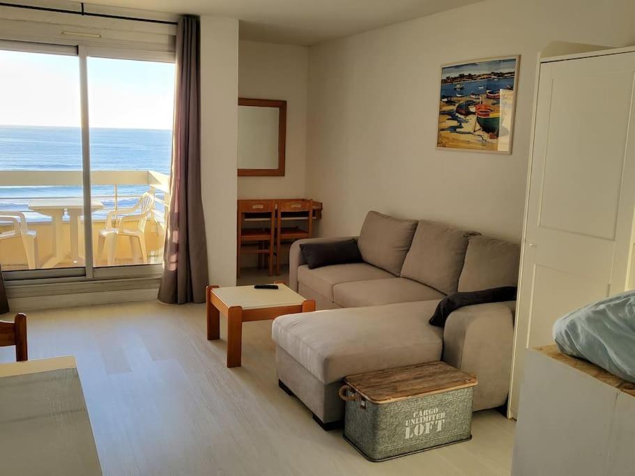 a living room with a couch and a view of the ocean at Biarritz centre balcon vue mer, piscine, plage in Biarritz