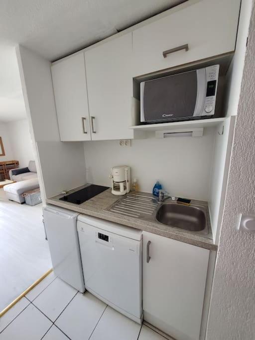 a small kitchen with a sink and a microwave at Biarritz centre balcon vue mer, piscine, plage in Biarritz