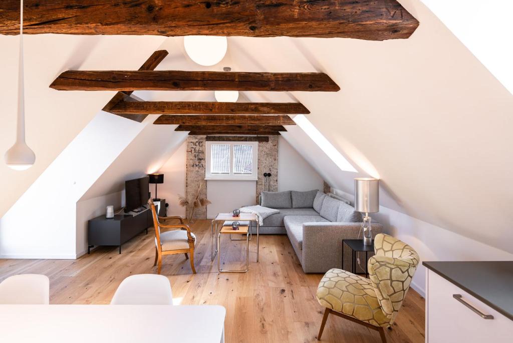 uma sala de estar no sótão com paredes brancas e vigas de madeira em Nicolai Suite - Schrangen-Suites-1389 em Lüneburg