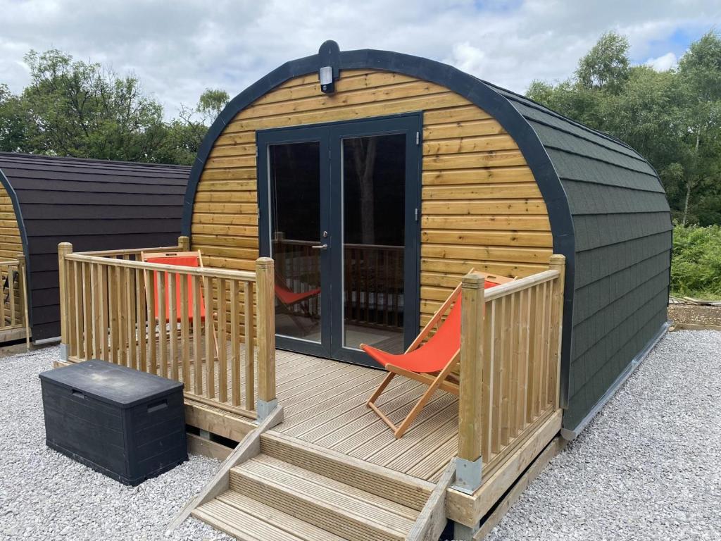 eine kleine Holzhütte mit einer Terrasse und einem Stuhl in der Unterkunft Sky Pod 1 Pet Friendly in Neath