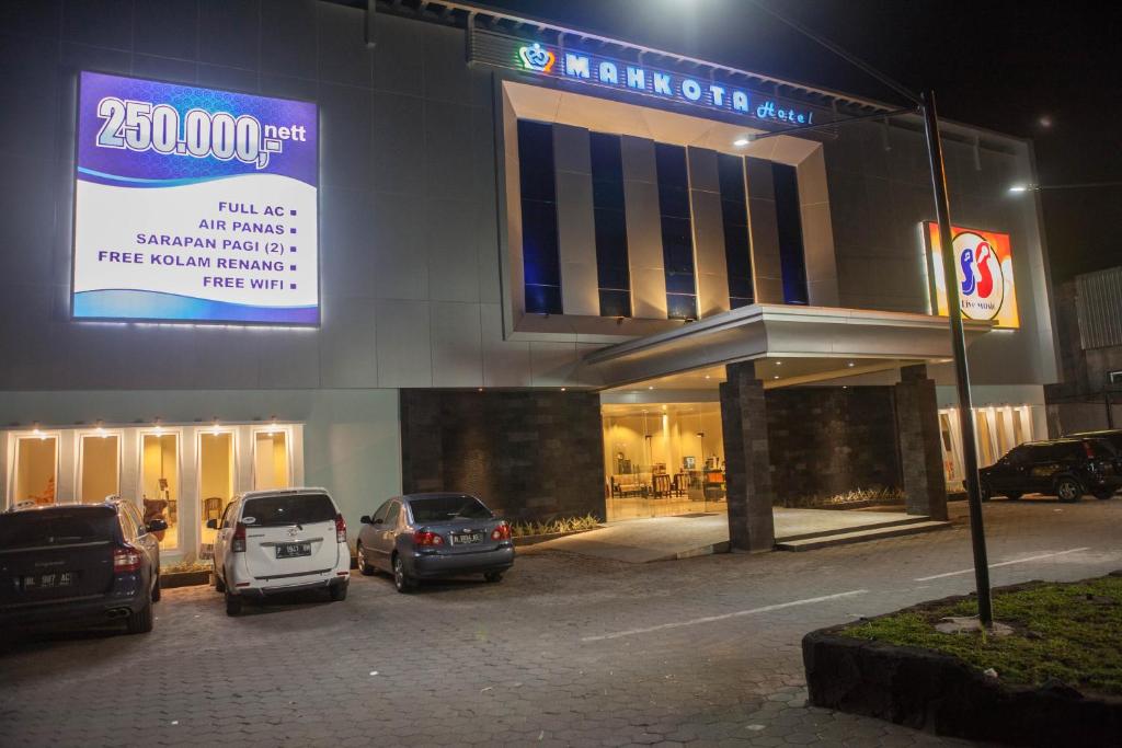 a parking lot with cars parked in front of a building at Mahkota Hotel in Genteng-kulon