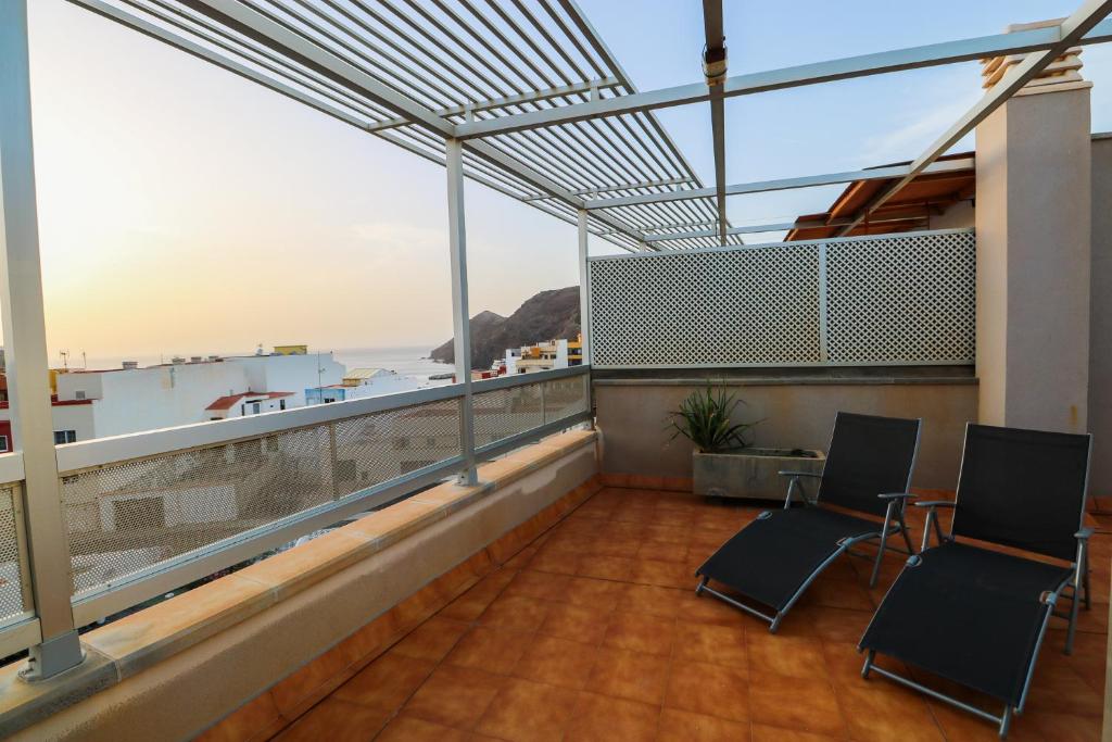 balkon z 2 krzesłami i widokiem na ocean w obiekcie Sardina attic flat pool&solarium w mieście Gáldar