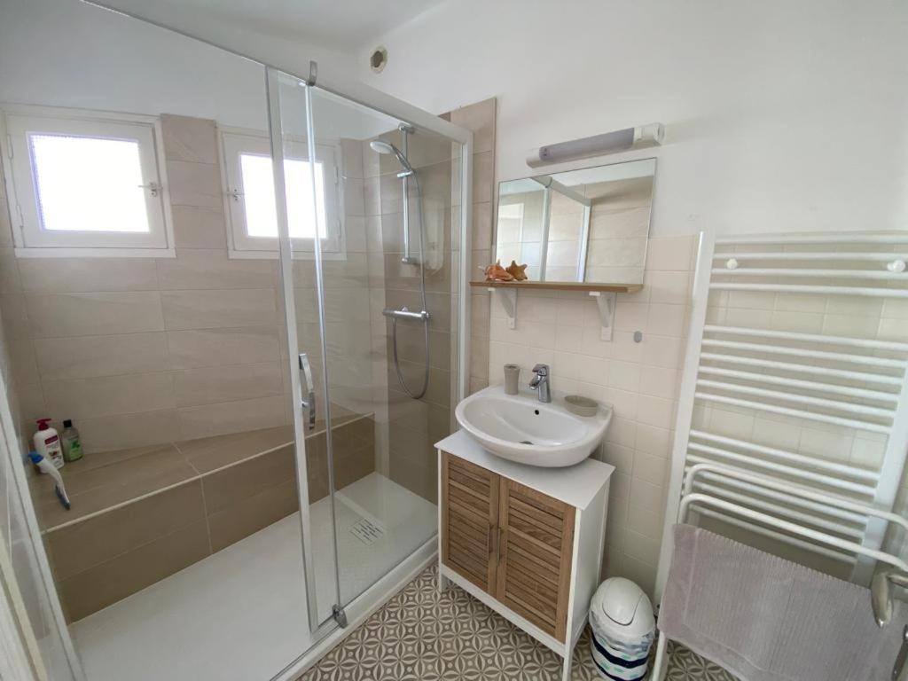 a bathroom with a glass shower and a sink at Ty Gavrinis - T2- Centre Bourg - 100m de la mer in Larmor-Baden