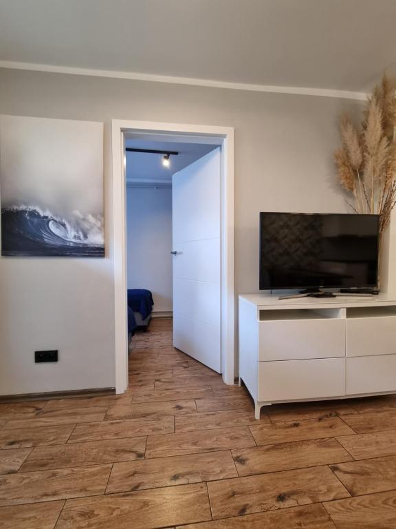 een woonkamer met een televisie en een dressoir met een televisie bij Apartament Marina Hel in Hel