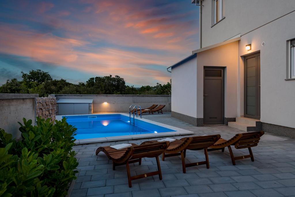 eine Terrasse mit einem Pool und Stühlen sowie ein Haus in der Unterkunft Holiday house Mareta - outdoor swimming pool, 4 bedrooms, WIFI in Jadrija