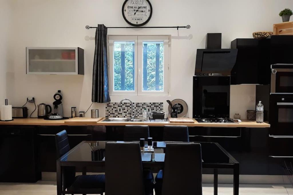 eine Küche mit einem Tisch und einer Uhr an der Wand in der Unterkunft DUPLEX COSY Confort PISCINE in Caderousse