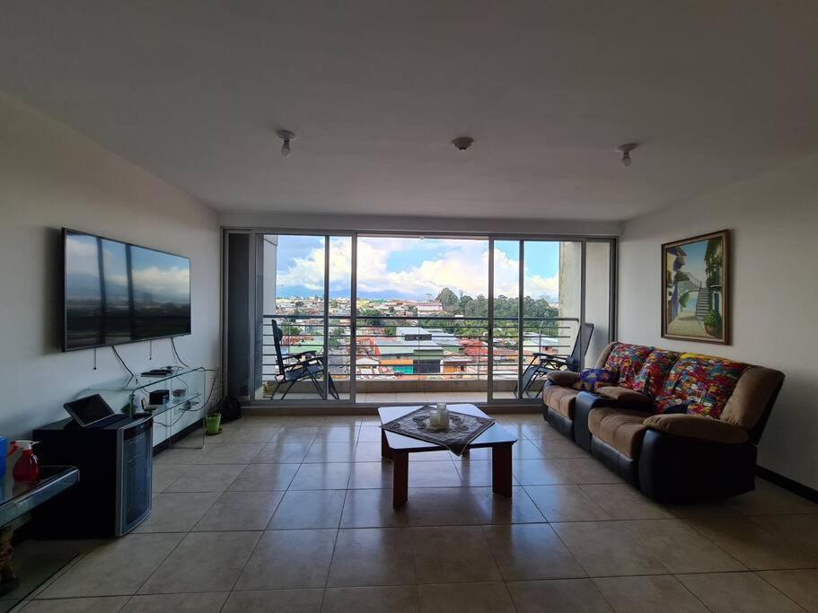 a living room with a couch and a large window at Apartment with city view in Oasis de San José in San José