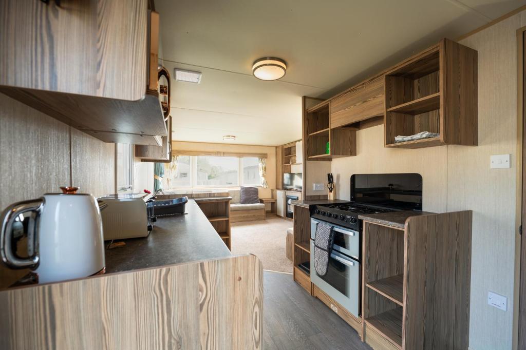 a kitchen with wooden cabinets and a stove top oven at Waterside, Thorpe Park Cleethorpes Static Caravan in Cleethorpes