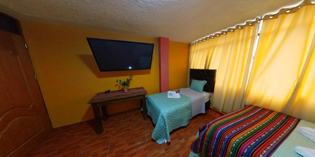 Habitación con cama, mesa y TV. en Yacumama Santa Teresa, en Santa Teresa
