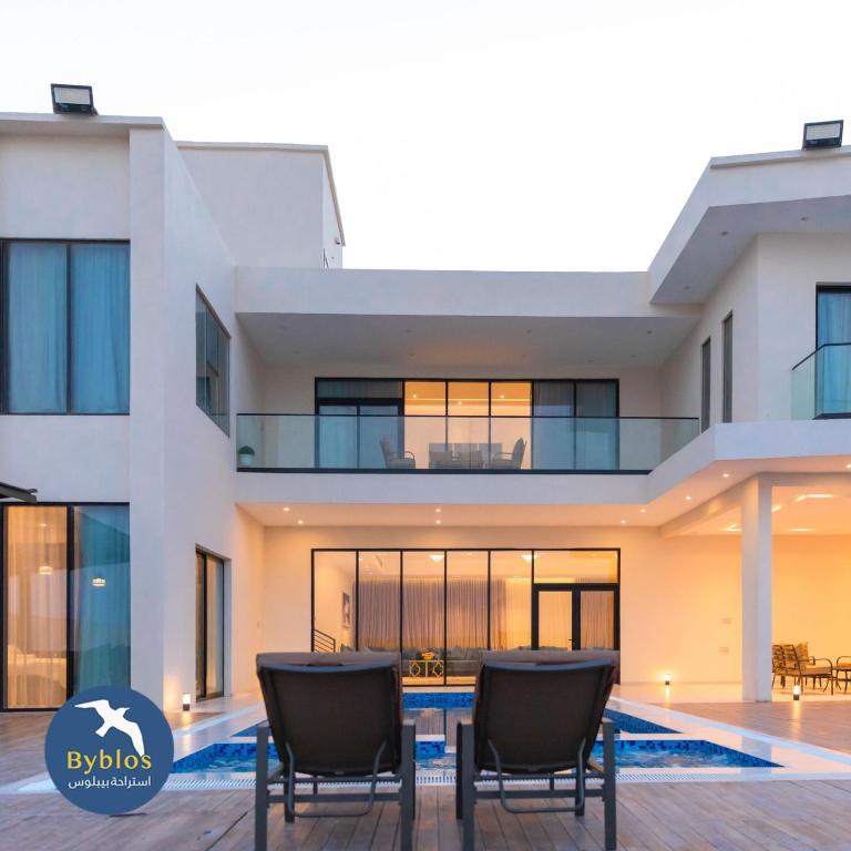 een huis met twee stoelen ervoor bij Byblos Villa Resort in Al Ḩadd