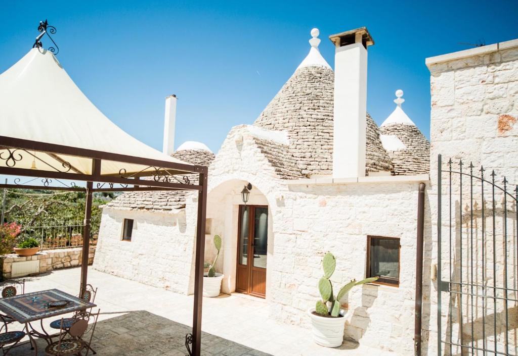 an external view of a stone house with a patio at Trulli Nuova Aia Resort in Alberobello