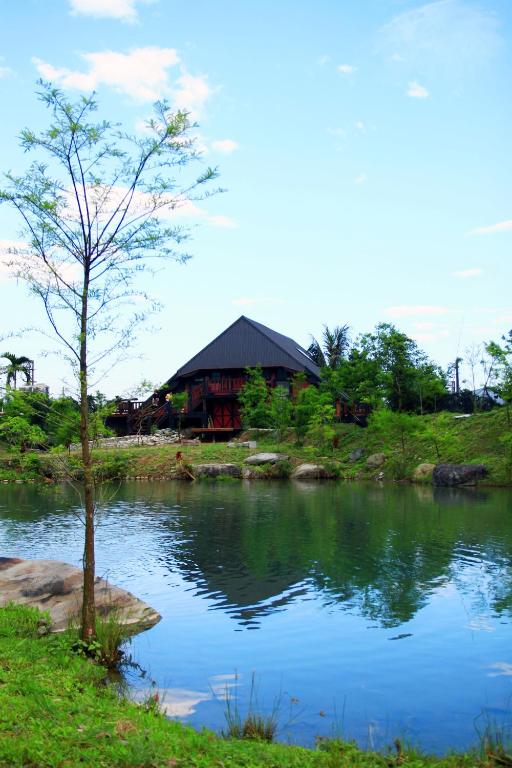 a small tree next to a lake with a building at Fanlin House in Jialin