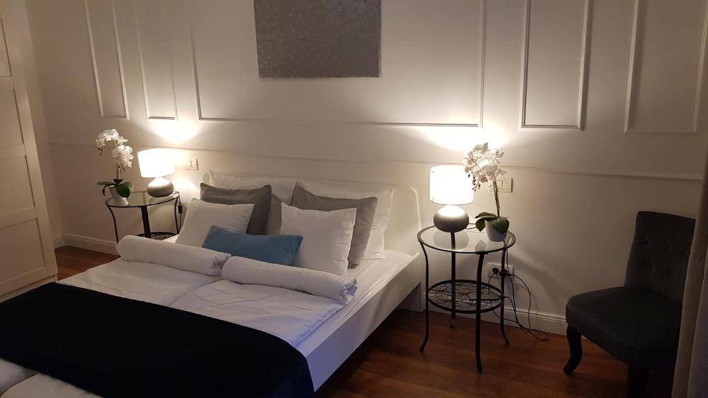 een slaapkamer met een bed met 2 lampen en een stoel bij Goldsmith Apartment in Boedapest