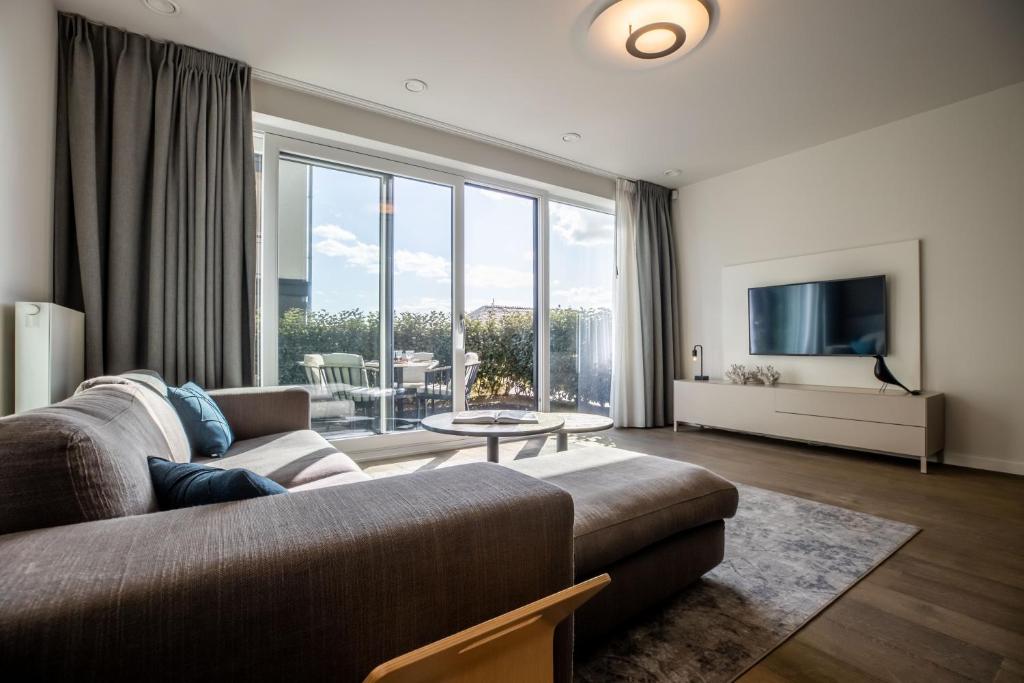 a living room with a couch and a large window at The Lagune, light and sunny apartment in the dunes in Cadzand