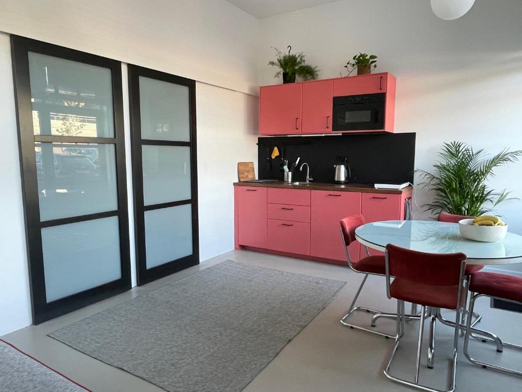una cocina con armarios rojos y una mesa con sillas. en Studio 28A5 with free parking place, en Ámsterdam