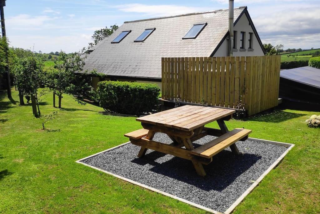 una mesa de picnic de madera en un patio con una casa en The Cow Hide @ Mill Burn Hollow. en Millisle