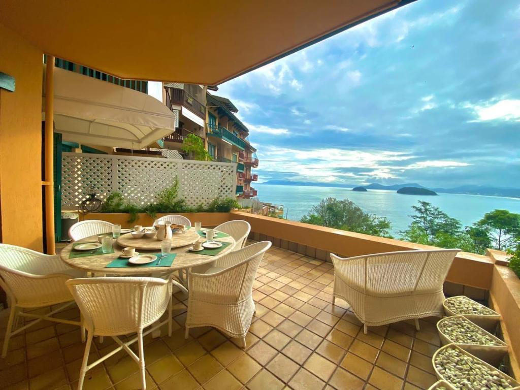 a patio with a table and chairs on a balcony at Apto c/ piscina e vista para o mar - Caraguatatuba in Caraguatatuba