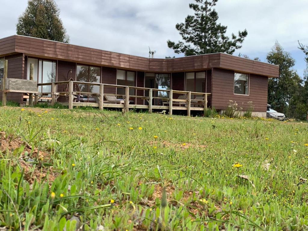 a wooden house with a field in front of it at Hermosa casa en parcela Algarrobo in Algarrobo
