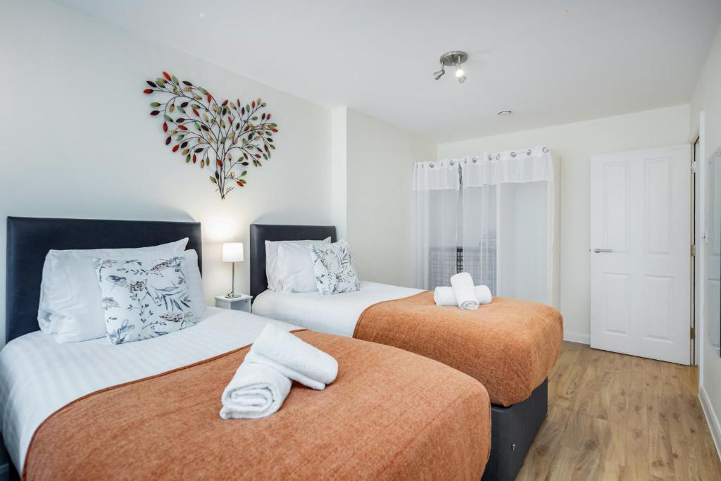 um quarto com 2 camas e toalhas em MPL Apartments - Queens Broadway F3 em Watford