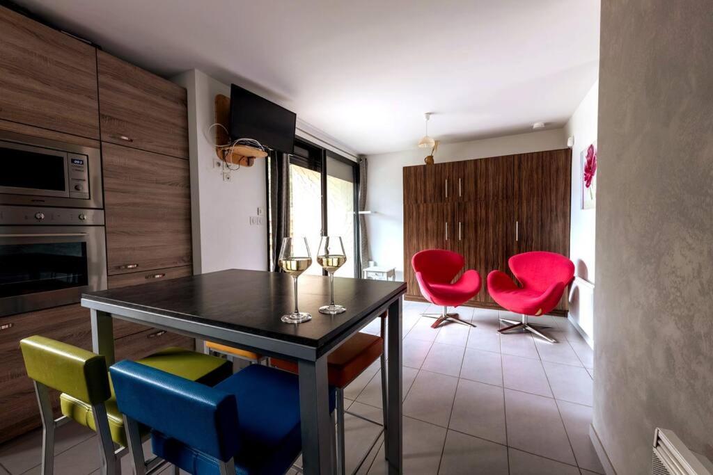 a kitchen with red chairs and a table with wine glasses at Pavillon douillet avec vue sur lac in Chorges