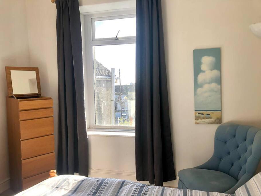 een slaapkamer met een blauwe stoel en een raam bij City living maisonette, The Nest in Swansea