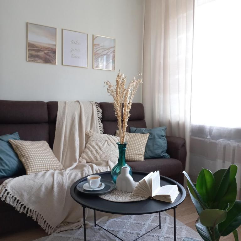 uma sala de estar com um sofá e uma mesa com um livro em Narva Relax Apartment em Narva