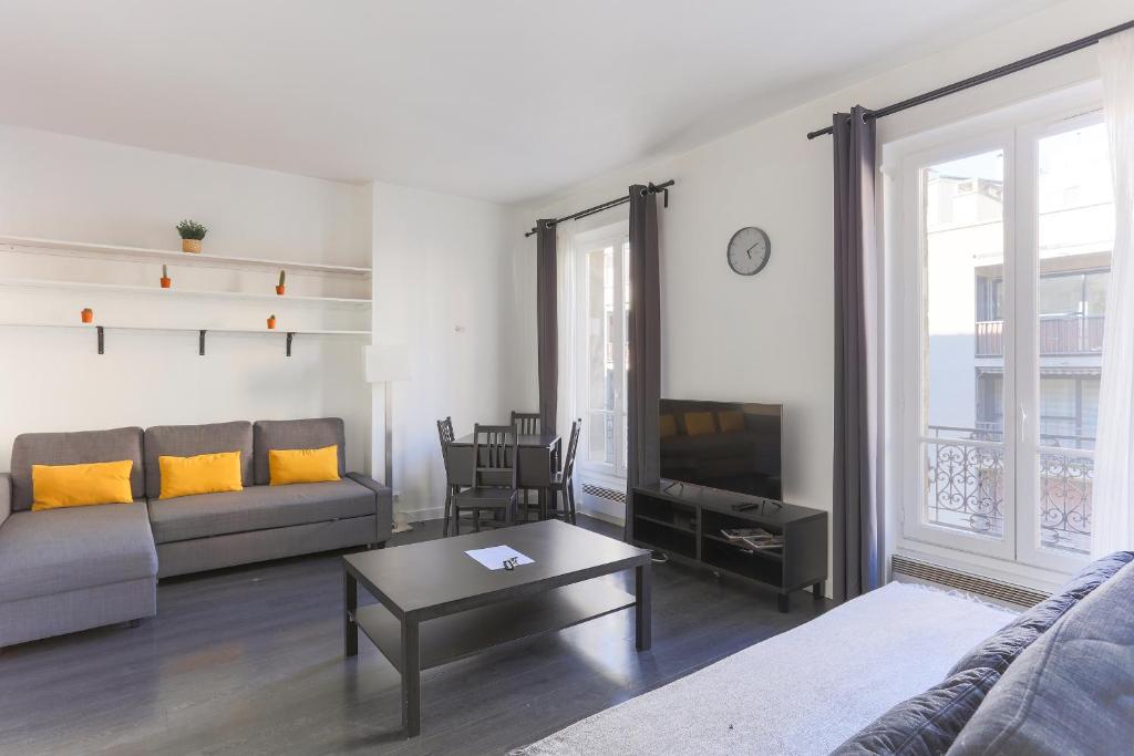 un salon avec un canapé et une télévision dans l'établissement Champs de Mars Appartement, à Paris