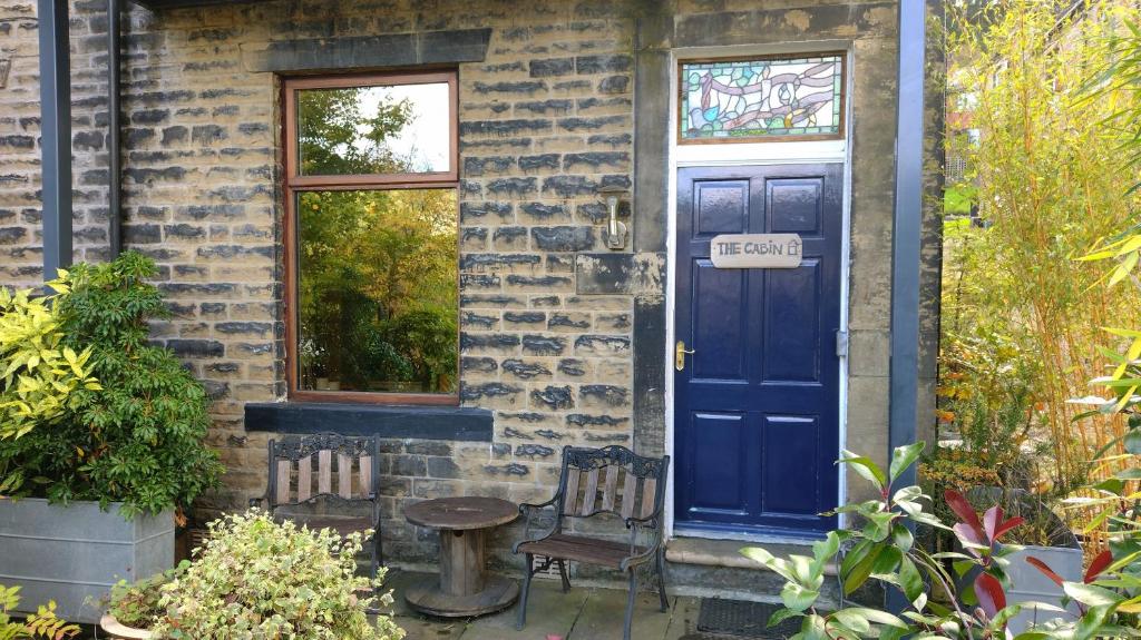 uma casa de tijolos com uma porta azul e uma mesa e cadeiras em The Cabin: Great Views,Garden,Close to Town, Quiet em Hebden Bridge
