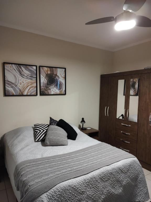 ein Schlafzimmer mit einem Bett mit drei Kissen darauf in der Unterkunft Casa 2 quartos com churrasqueira no centro de Serra Negra in Serra Negra
