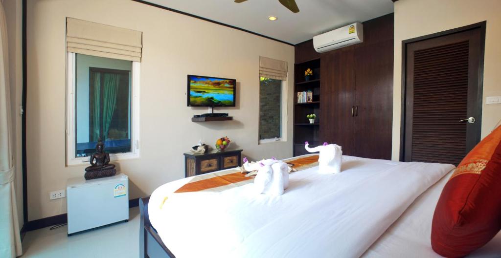 a bedroom with a large white bed with two stuffed animals on it at Samui Sunrise Seaview Villa in Chaweng