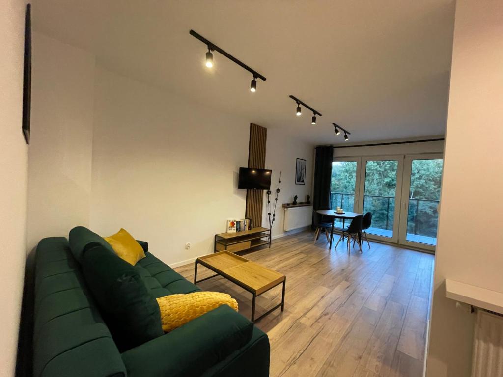 ein Wohnzimmer mit einem grünen Sofa und einem Tisch in der Unterkunft Apartament Park Poezji in Gliwice