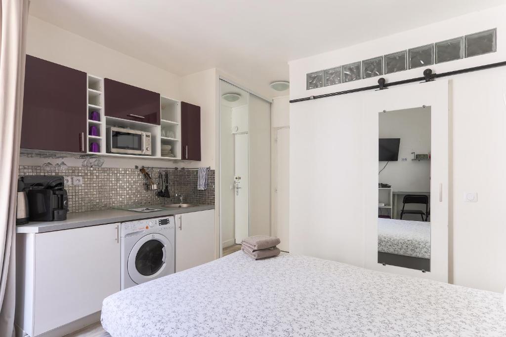 una cocina blanca con lavadora en una habitación en RASPAIL Cozy Flat en París