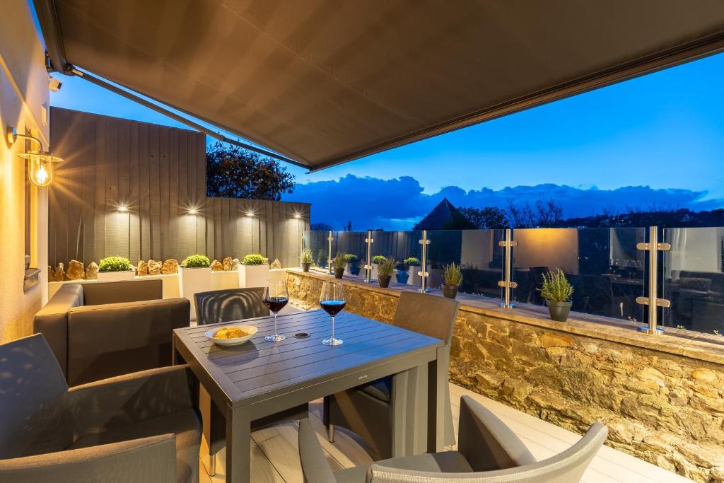un patio con una mesa con copas de vino. en Rutland Heights,A Fantastic Modern Coastal House, Sea Views, Garden, Terraces, 2x Allocated Private Parking Spaces plus Free Private use of Electric Vehicle Point Meadfoot Beach only 5mins away! Also Shops, Bars and Restaurants just a 10 minute walk! en Torquay