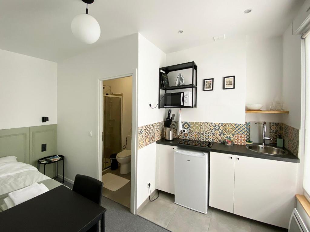 - une cuisine avec des placards blancs, un lavabo et un lit dans l'établissement VILLA VLAS - Chambre d'Hôte - Limoges, à Limoges