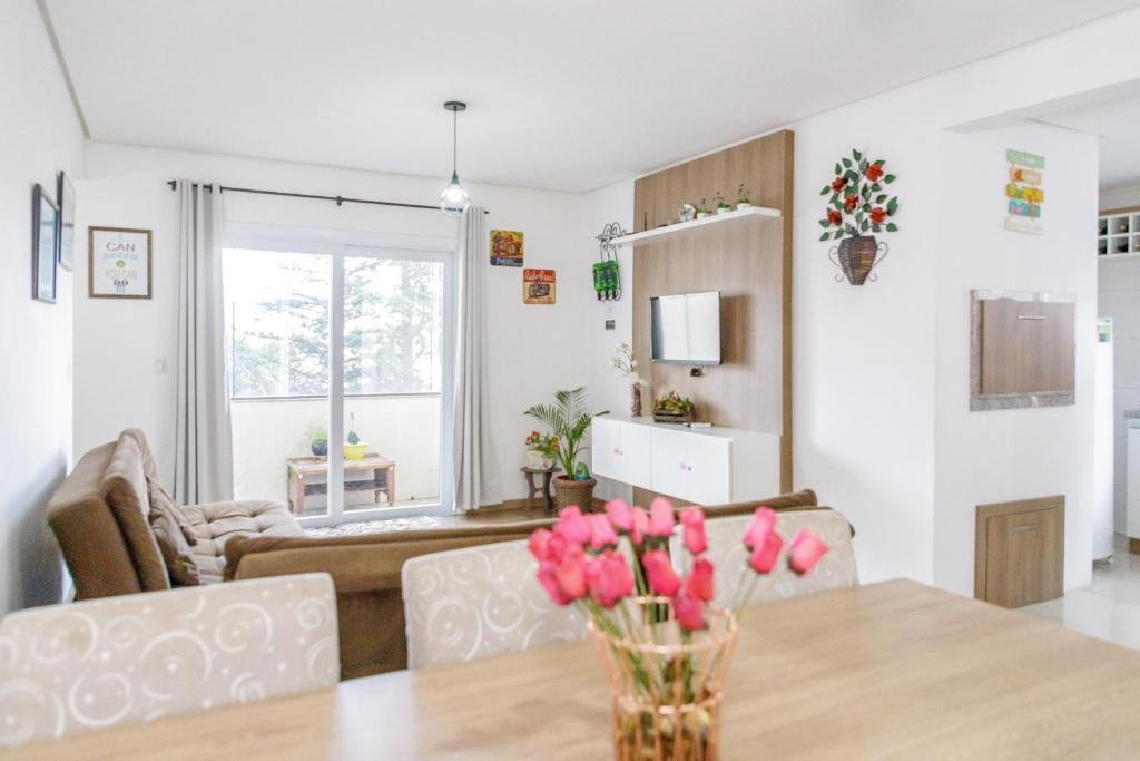 a living room with a table with pink flowers on it at Lindo residencial no centro de Gramado in Gramado