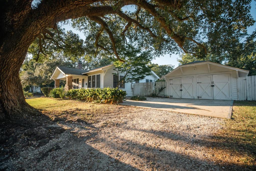 una casa con un garaje blanco y un árbol en Gulf Coast Craftsman - Cozy, Charming & Central!, en Gulfport