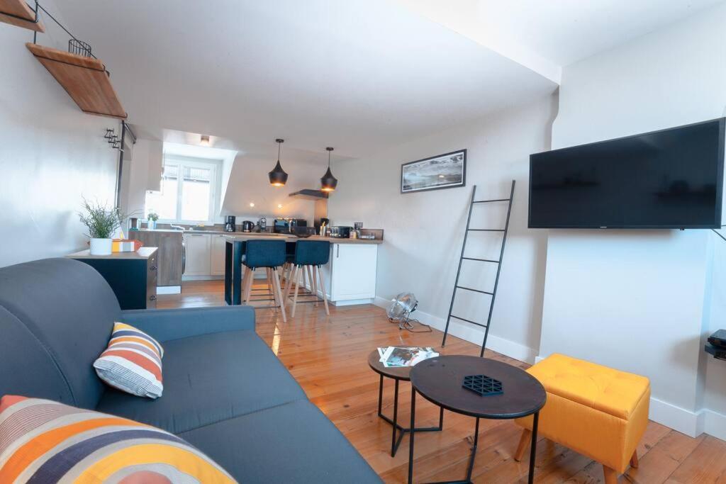 a living room with a blue couch and a kitchen at Coup de Cœur assuré pour ce T2 rénové Hyper centre in Biarritz