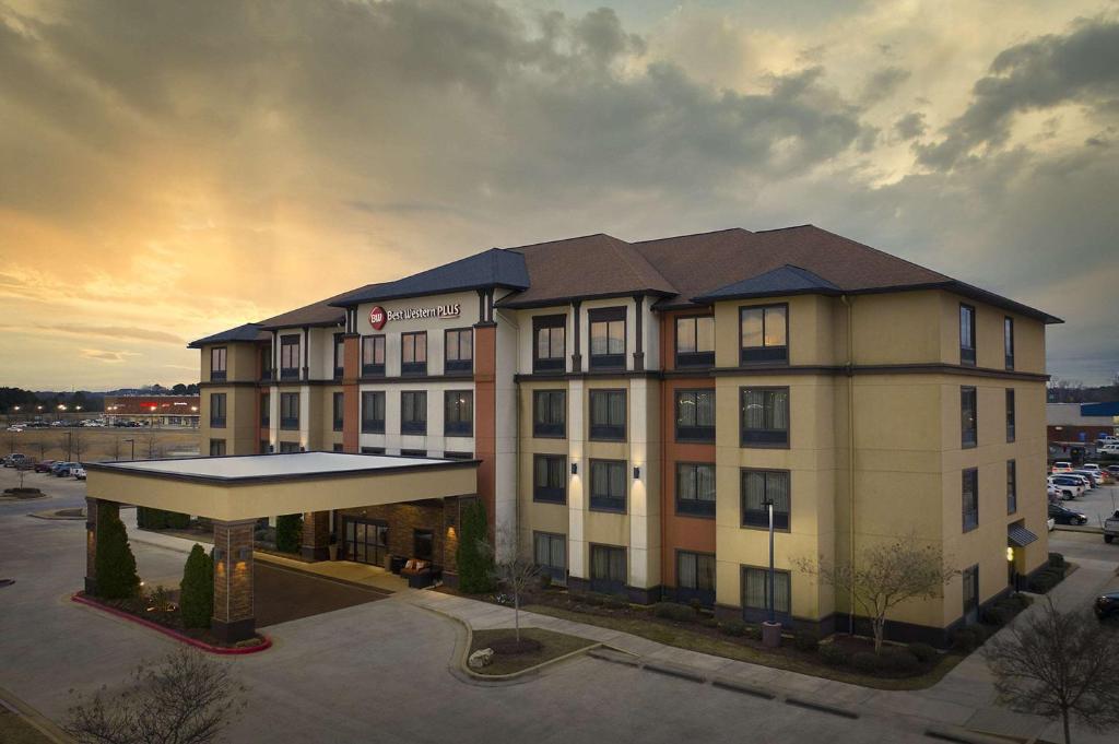 a hotel building in a parking lot with a sunset at Best Western Plus Tupelo Inn & Suites in Tupelo